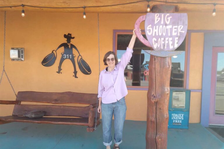 Susan Vittitow standing next to giant coffee cup sign at Big Shooter Coffee